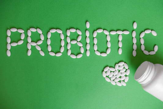 pills spelling out the word probiotic on a green background 
