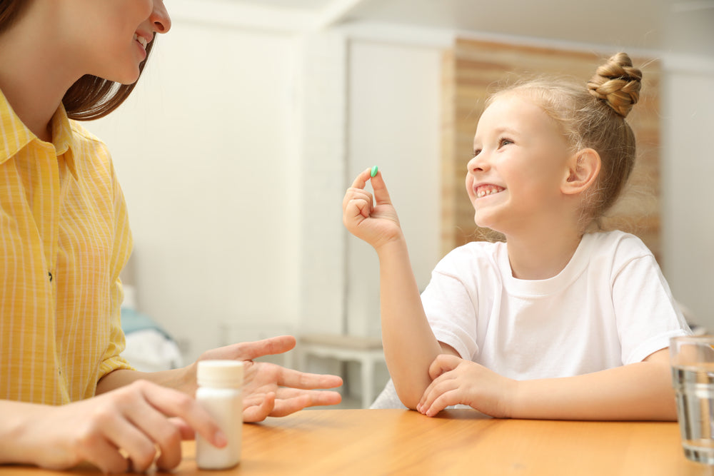 child holding a blue pill smiling and looking at mother